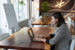 woman in gray and white striped long sleeve shirt using silver macbook