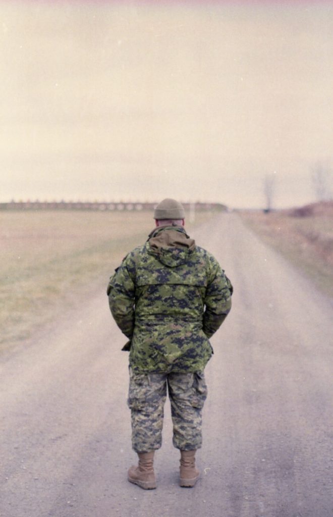 man in green camouflage uniform standing on road during daytime