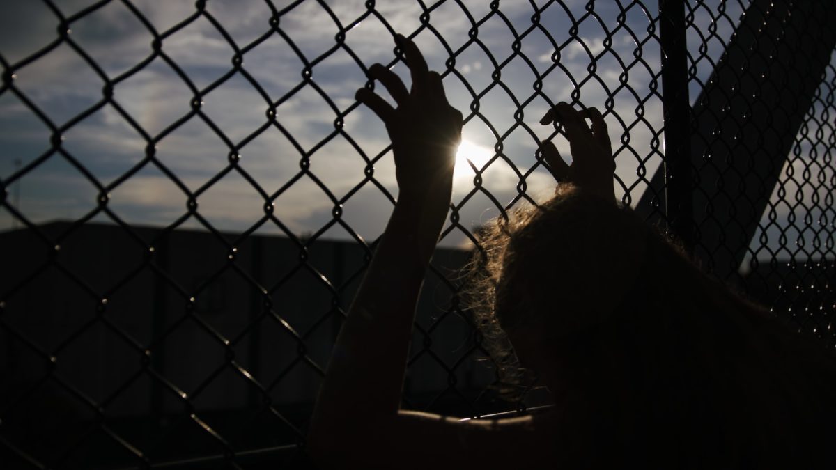 person holding on chain link fence