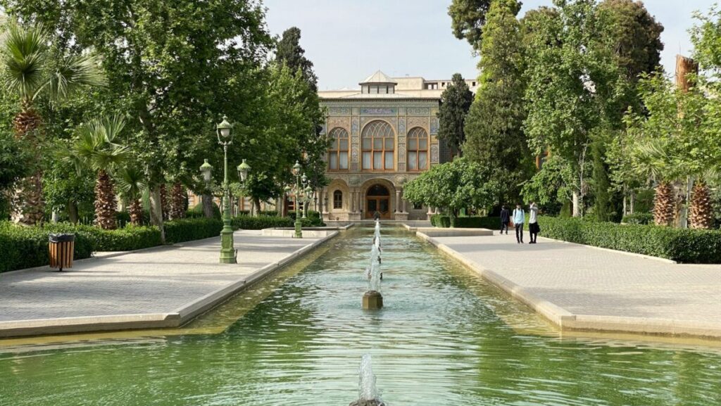 a large building with a fountain in the middle of a pond