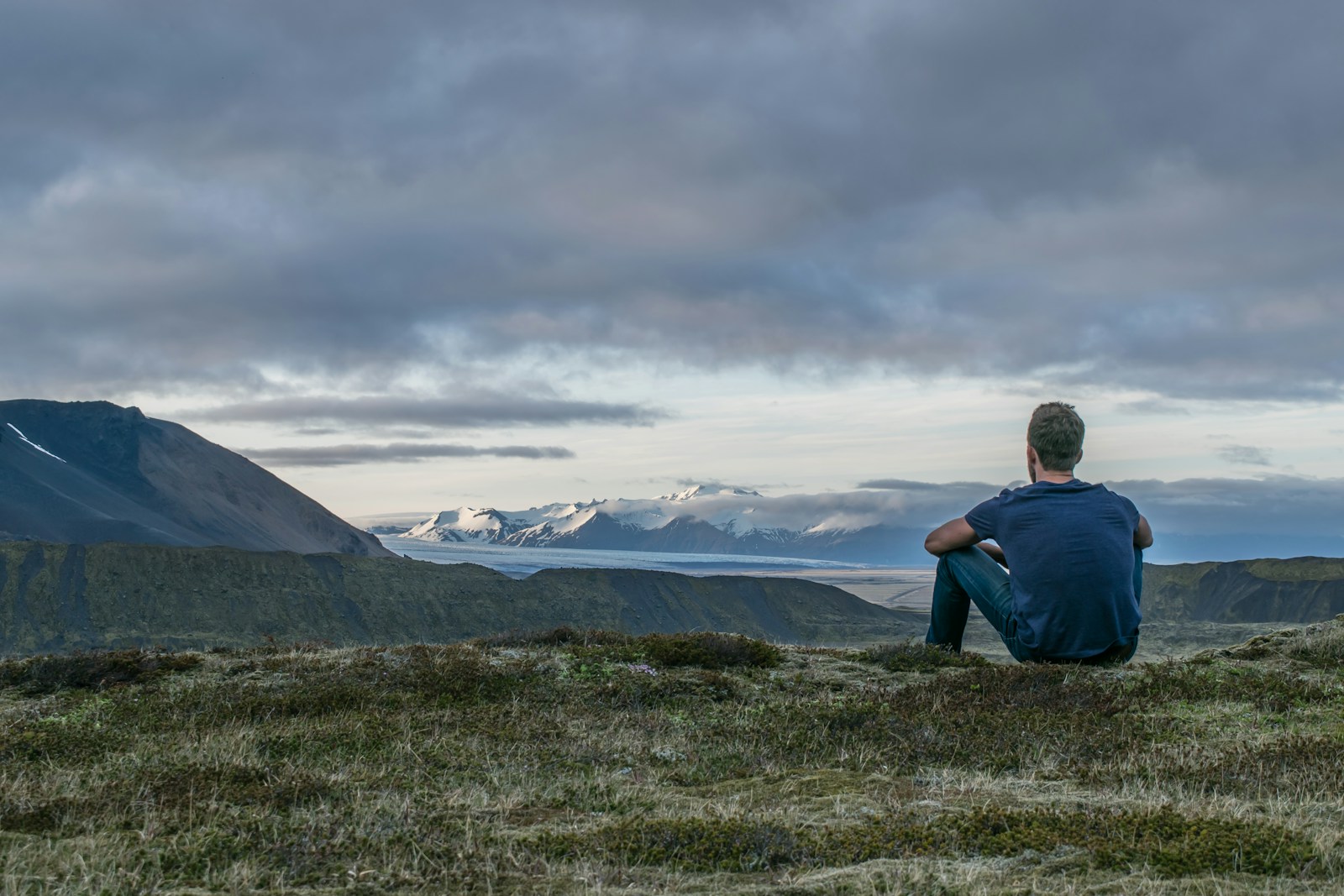 man sitting on the top of a mountain thinking