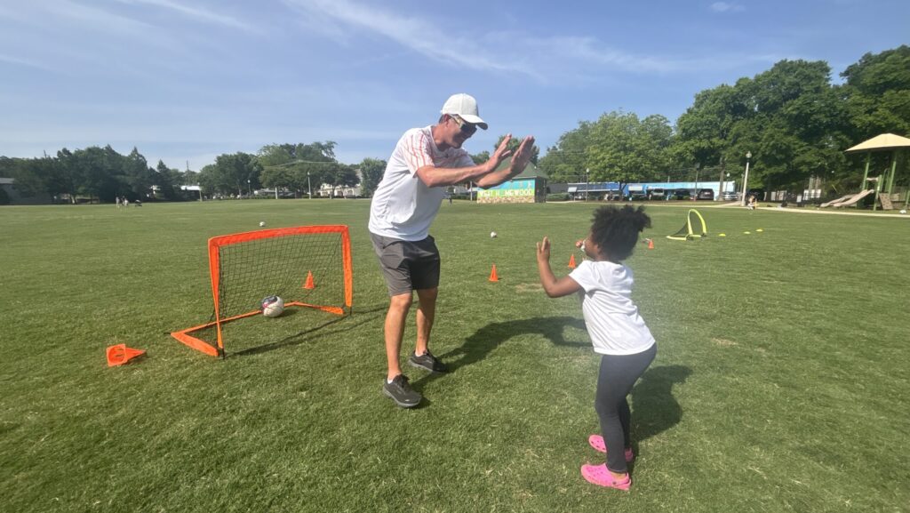 Coach cheering on young child playing soccer