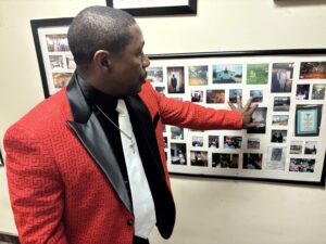 Man giving tour of building and pointing to photos framed on the wall