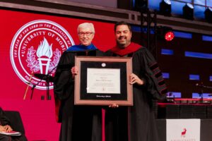 Rick Lance and Charles Smith holding framed doctor of humane letters on the stage after the presentation